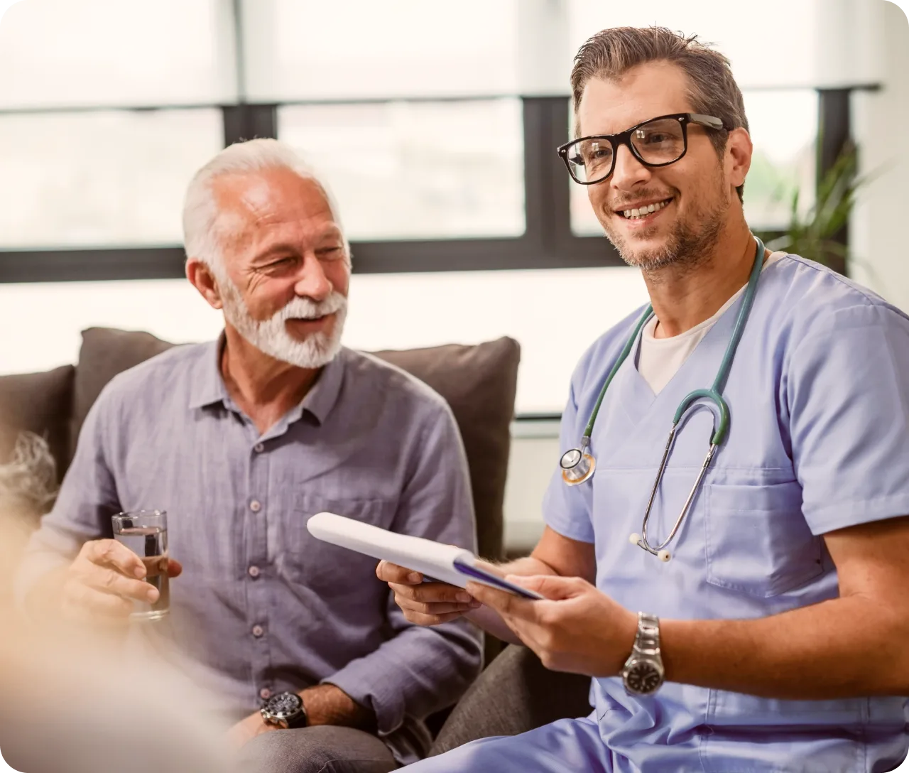 An older patient talking with his clinician on a sofa